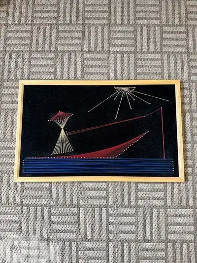 Vintage handmade string art wall decor on black velvet background
